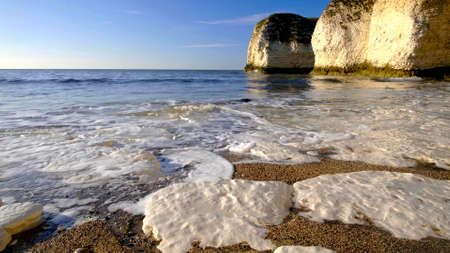 A close-up on the foam of the ocean on the beach