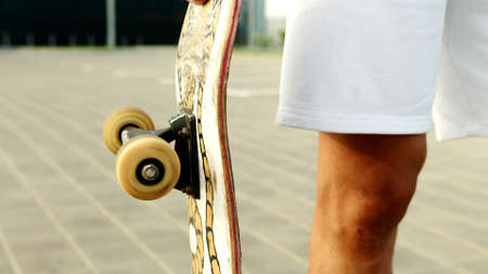 A close up on a skateboard next to a leg of a man