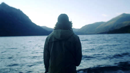 The back of a man who is watching a lake
