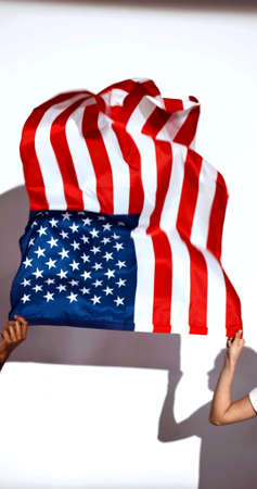 A vertical photo of hands of a man and a woman which are holding a US flagの写真素材