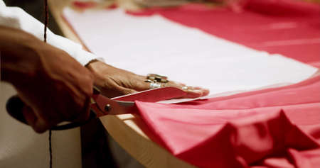 A woman is cutting fabric with a scissorsの写真素材