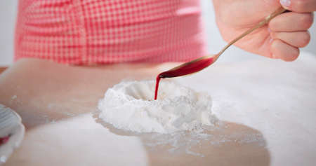 A woman is cooking with plain flour on a table