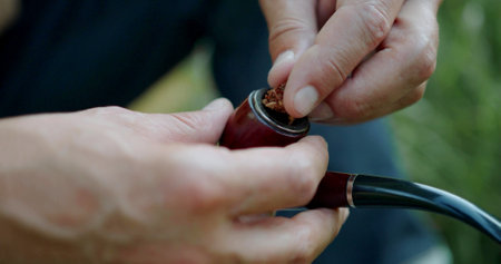 Man is putting tobacco in a pipeの写真素材