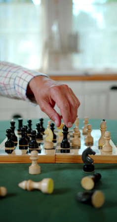 A vertical photo of a hand which is playing chess
