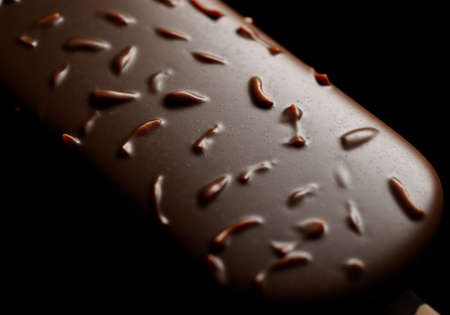 Close-up view of a chocolate ice cream  on a stick covered with nuts, almond, hazelnut. Studio lighting. Black background. 3D realistic rendering illustration.の写真素材