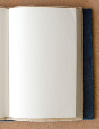 blank book page  open on a brown textured surfaceの写真素材