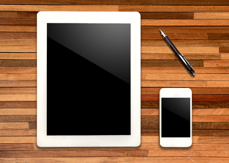 Digital tablet and smart phone on wooden table with penの写真素材