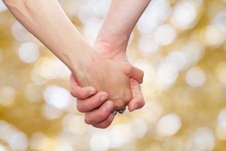 couple holding hands  on glittering background.background with bokeh defocused lightsの写真素材
