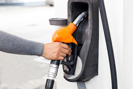 Closeup of woker hand holding gas pump nozzle at gas station.の写真素材