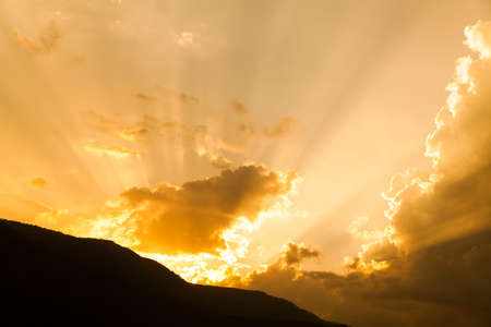 Beautiful dramatic sky with sun rays. over mountainの写真素材