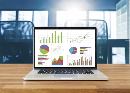 Laptop on wooden table showing charts and graph against office background ,Analysis Business Accounting, Statistics Concept.の写真素材