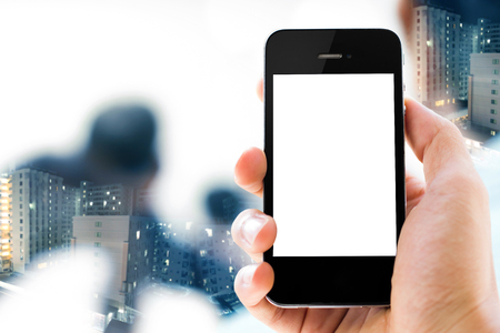 Close-up Hand holding white screen smart phone with double expose of  business people in conference room  backgroundの写真素材