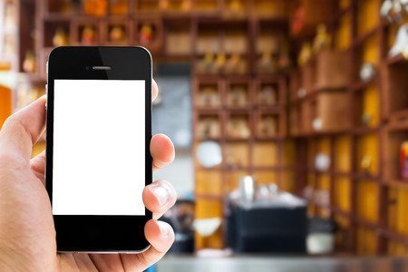 Close uphand holding phone with blank screen on coffee cafe backgroundの写真素材