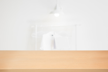 Empty wooden table and modern white clean room background with shirt hanging, lamp, book,  Ready for product montageの写真素材