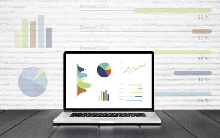 Laptop on wooden table showing charts and graph colorful graphics, Analysis Business Accounting, Statistics Concept.の写真素材