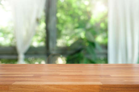 Empty of wood table top on blur of abstract green from garden with sunlight and curtain window , product display, Ready for product montage.の写真素材