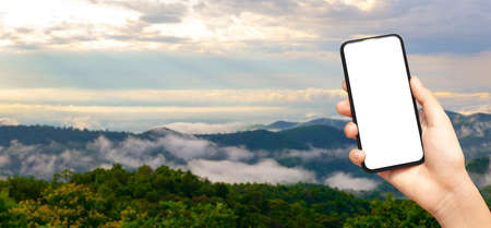 beautiful female hand holding smart phone with black screen against nature moutain with clound background, technology and nature concept. banner and copy spaceの写真素材