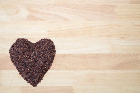 Thai black jasmine rice (Rice berry) heart shape on wooden backgroundの写真素材