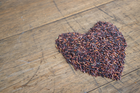 Thai black jasmine rice (Rice berry) heart shape on wooden backgroundの写真素材