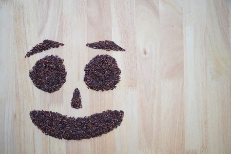 Thai black jasmine rice (Rice berry) smile shape on wooden backgroundの写真素材