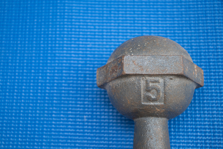 Iron dumbbell 5 kilograms on blue yoga mat (Fitness exercise equipment)