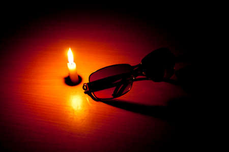 Single Candle on table with sunglass in front depicting blindness as a themeの写真素材