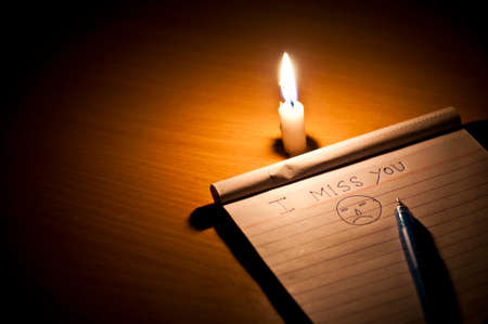 Single Candle with pen and pad containing emotional write-upの写真素材