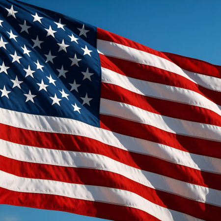 American Flag waving in the wind on blue sky background. Close up.の素材