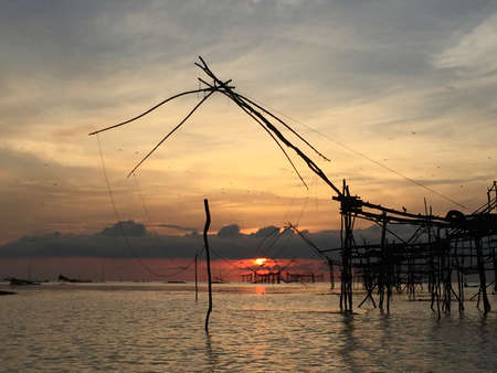 Old culture traditional fishing at lake by wooden square dip net in the sunrise of morning time. Good morning the sun!の写真素材