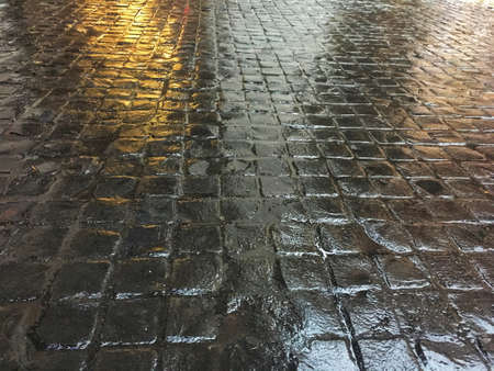 Wet dark brown stone tile on the floor. Lighting reflection on rough walkway surface.の写真素材