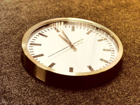 White wall clock with silver edge on gray background. Vintage old style concept.の写真素材