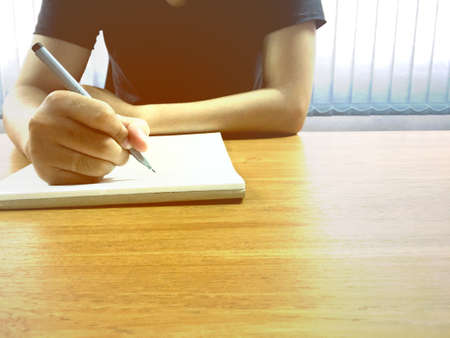 Young businessman holding the pen and hand writing on notebook in office.の写真素材