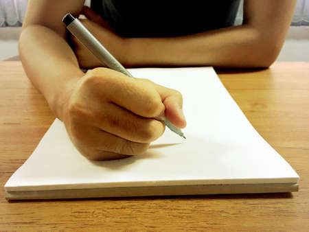 Young businessman holding the pen and hand writing on notebook in office.の写真素材
