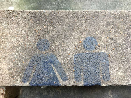 Restroom sign with man and woman blue color painting on pebble cement floor.の写真素材