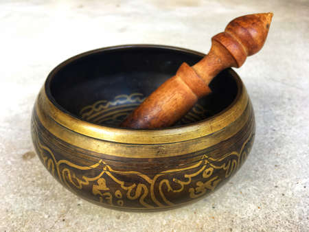 Handcrafted brass singing bowl with wooden stick put on the floor. Isolate backgroundの写真素材