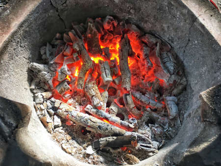 Red fire and cinder in baked clay kiln. Burned charcoal made from dry branch of tree.の写真素材