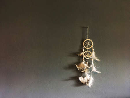 White dream catcher with feather hang on nail on gray wall background.の写真素材