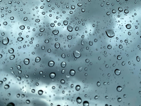 Blurred water drop on the car glass background, blurred of outside cloudy sky through car window during raindrop.の写真素材