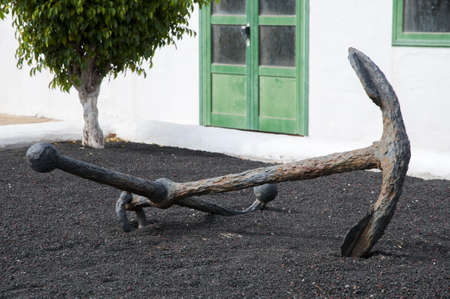 an anchor monument is set in a garden with volcanic soil
