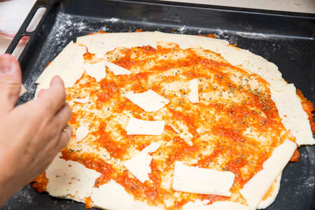 preparing the pizza dough with cheese on the tableの写真素材