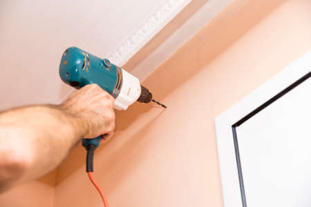 worker making a hole in the wall to mount curtainsの写真素材