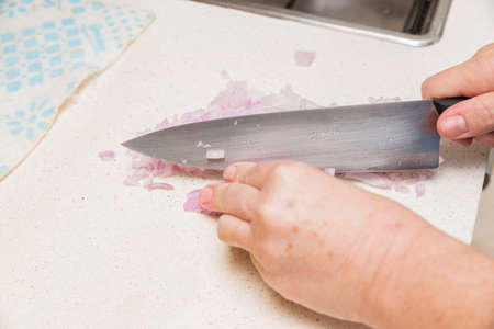 hands cutting onion diced small