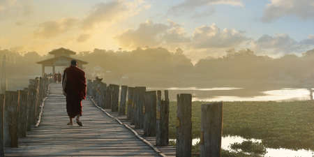 Monk walking on a bath bridge at Mandalay, Myanmarの写真素材