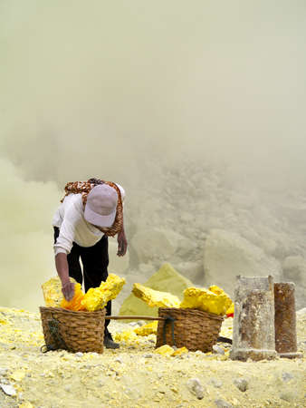 MINER COLLECTING SULFUR ON KAWAH IJEN VOLCANO IN JAVA ISLAND-INDONESIAの写真素材