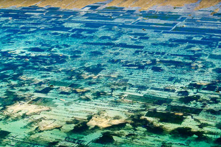 view of the coast with beach and coral at bukit in bali -farmer in boat harvesting sea weed in...