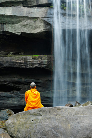 Monks doing meditation in front of a waterfall in thailandの写真素材