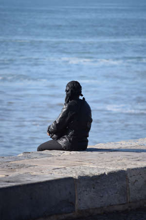 Lonely women sitting on a sea wall watching the oceanの写真素材