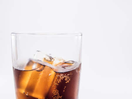 close up two of thirds soft drink is cool and ice cubes  in glass on white backgroundの写真素材