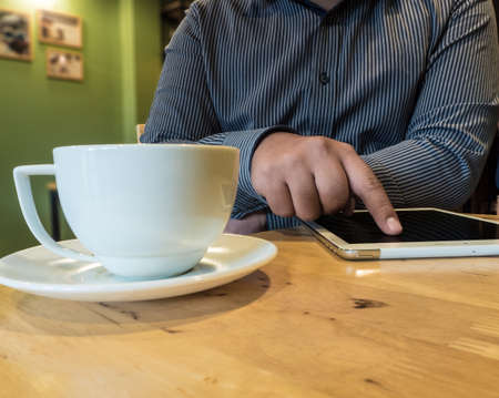 business man using internet on tablet in cafe coffee shop with white coffee cupの写真素材