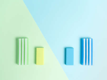 big and little green eraser and blue eraser on green and light blue background.の写真素材